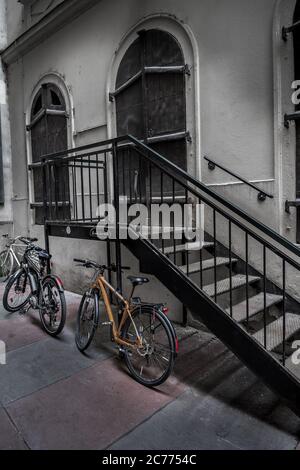 Vieux vélos garés sur des escaliers en fer sous le bâtiment historique avec portes massives verrouillées dans la ville intérieure de Vienne en Autriche Banque D'Images