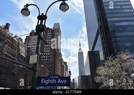 Vue sur l'Empire State Building depuis la huitième avenue. D'un côté se trouve un bâtiment noir moderne et des bâtiments art déco plus anciens de l'autre. Banque D'Images