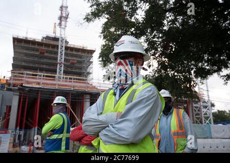 Austin, TX USA 14 juillet 2020 : les ouvriers du bâtiment écoutent les consignes de sécurité pendant qu'ils se préparent à un quart de huit heures dans la chaleur de 105 degrés du Texas. Les équipages sont sur le deuxième étage d'un immeuble de 53 étages prévu, car ils prennent des précautions contre la pandémie du coronavirus. Banque D'Images