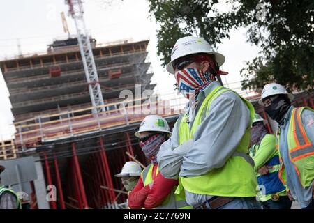 Austin, TX USA 14 juillet 2020 : les ouvriers du bâtiment écoutent les consignes de sécurité pendant qu'ils se préparent à un quart de huit heures dans la chaleur de 105 degrés du Texas. Les équipages sont sur le deuxième étage d'un immeuble de 53 étages prévu, car ils prennent des précautions contre la pandémie du coronavirus. Banque D'Images