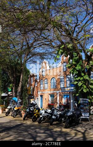 Motos garées sur la rue Doria Vasconcelos à l'ombre des arbres, juste en face du bâtiment Holam Tour et de la boutique de cadeaux Casa Bela dans le centre-ville, Holambra. Banque D'Images