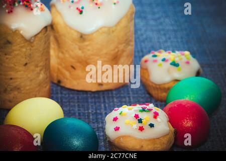 Gâteaux de Pâques avec glaçage sucré et œufs colorés sur fond bleu foncé Banque D'Images