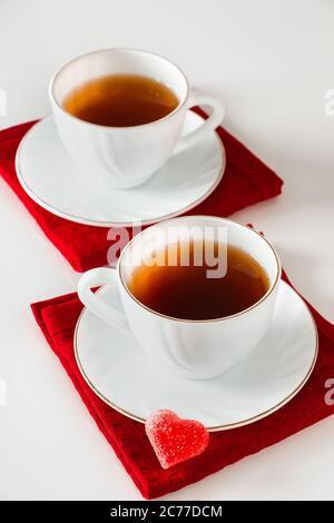 Deux tasses de thé blanches sur fond blanc. Marmelade en forme de coeur, symbole de la Saint-Valentin et de l'amour. Le concept d'une rencontre de deux amoureux. Banque D'Images