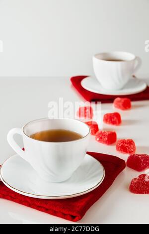 Deux tasses de thé blanches sur fond blanc. Marmelade en forme de coeur, symbole de la Saint-Valentin et de l'amour. Le concept d'une rencontre de deux amoureux. Banque D'Images