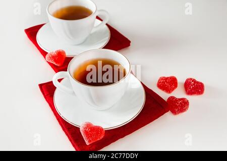 Deux tasses de thé blanches sur fond blanc. Marmelade en forme de coeur, symbole de la Saint-Valentin et de l'amour. Le concept d'une rencontre de deux amoureux. Banque D'Images