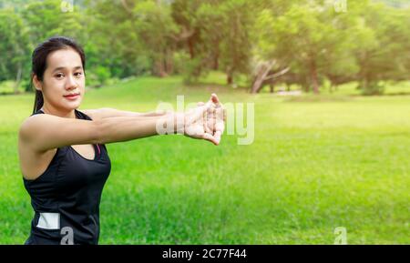 Jeune fille asiatique qui étire ses muscles avant de faire du jogging à l'extérieur, qui s'échauffe pour s'entraîner le matin, s'asseyant sur un sentier dans le parc. Jeunes femmes asiatiques en bonne santé Banque D'Images