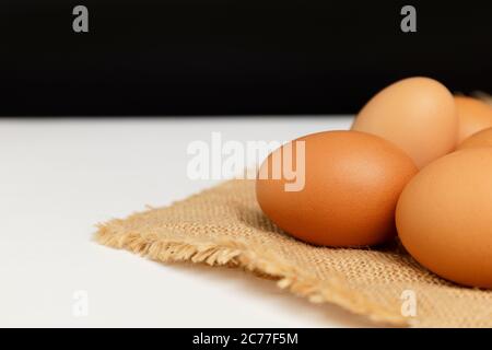 Gros plan sur les œufs de poulet frais sur la nappe en lin et la table blanche avec espace de copie . Banque D'Images