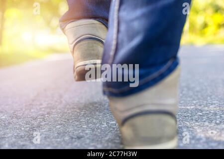 Homme en jeans et baskets de sport marchant sur la route. Concentrez-vous sur les baskets. Avec espace de copie pour le texte ou la désie Banque D'Images