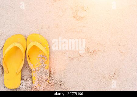 Vacances d'été sur la plage les sandales jaunes sur la plage ont le coucher du soleil Banque D'Images