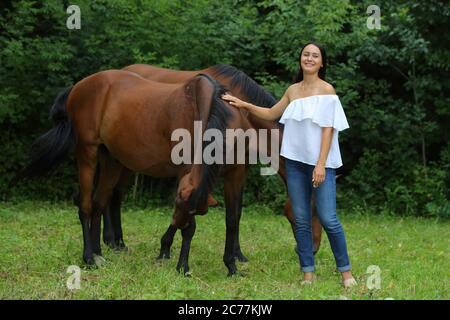 Jolie fille sourit à la manne du cheval sur le terrain. Bride, adulte. Banque D'Images