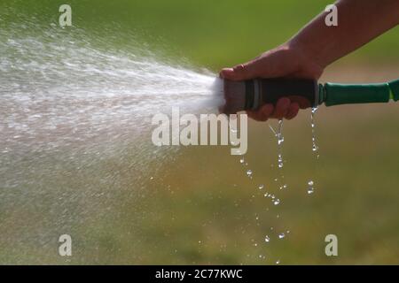 Un homme pulvérise de l'eau dans un tuyau sur une photo de gros plan. Banque D'Images