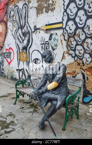 La figure ébréchée d'un homme assis, fatigué devant des graffitis sauvages dans Thalang Road dans la vieille ville (Chinatown) de Phuket Town, Phuket, Thaïlande Banque D'Images