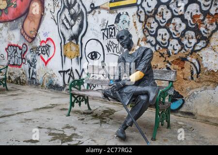 La figure ébréchée d'un homme assis, fatigué devant des graffitis sauvages dans Thalang Road dans la vieille ville (Chinatown) de Phuket Town, Phuket, Thaïlande Banque D'Images