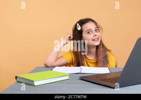 Jolie fille scolaire élégante étudiant les devoirs mathématiques pendant sa leçon en ligne à la maison, distance sociale pendant la quarantaine, auto-isolement, éducation en ligne Banque D'Images