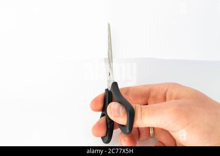 ciseaux entre les mains d'un homme et feuille blanche Banque D'Images