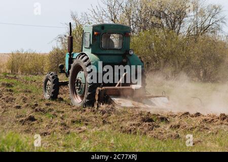 Un tracteur bleu ancien charrue un champ et cultive le sol. Agriculture. Banque D'Images