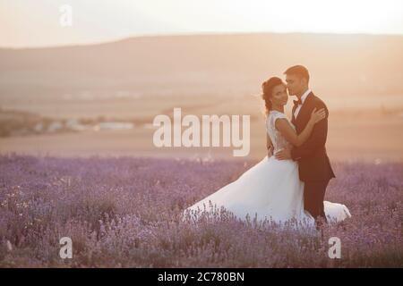 Couple de mariage dans un champ de lavande au coucher du soleil, mariée et marié Banque D'Images