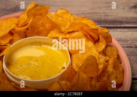 Croustilles sur un plateau rond et une casserole avec sauce au fromage. Gros plan Banque D'Images