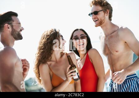 Les jeunes en maillots de bain ont du bon temps à boire de la bière, se sentant incroyable Banque D'Images