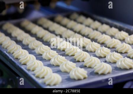 Le beurre fait tourner les biscuits sablés fouettés sur le plateau de la chaîne de production. Mise au point sélective. Banque D'Images