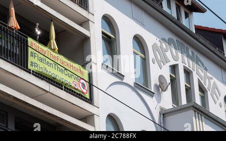 Hanovre, Allemagne. 14 juillet 2020. Une bannière disant '#StayTheFuckHome #FlatTheCurve #Risk Group' est accroché sur le balcon d'un appartement à proximité immédiate d'une pharmacie. Credit: Hilal Özcan/dpa/Alay Live News Banque D'Images
