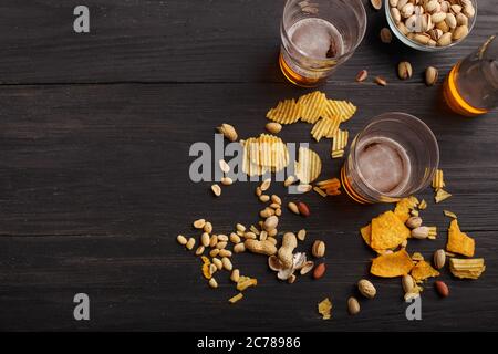 Boissons pour deux. Les verres avec support à bière sur table sombre, près sont bouteille et pistaches dans l'assiette Banque D'Images