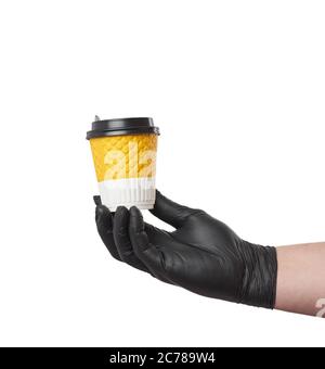 main dans un gant en latex noir tient une tasse en carton jetable et un couvercle en plastique sur fond blanc, livraison sûre et sans contact des commandes en ligne Banque D'Images