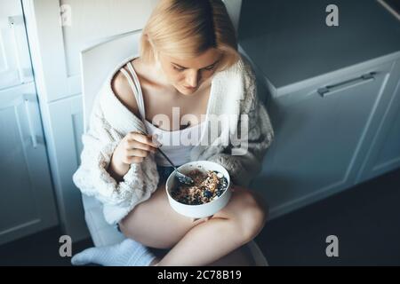 Vue de dessus photo d'une femme blonde caucasienne qui perd du poids en mangeant des céréales sur le sol Banque D'Images