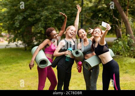 Heureux diverses filles prenant le selfie ensemble après la classe de yoga au parc Banque D'Images