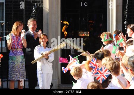 La flamme olympique rejoint le Premier ministre David et Samantha Cameron au numéro 10 Downing Street, porté par Ceri Davies qui a transmis la flamme à Florence Rowe. 25 juillet 2012 --- image de © Paul Cunningham Banque D'Images