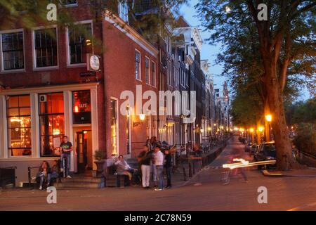 Scène nocturne sur les canaux d'Amsterdam, aux pays-Bas, en été. L'image illustre la vie nocturne décontractée typique d'Amsterdam. Banque D'Images