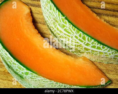 Deux tranches de melon de canteloup sur une planche à découper en bois avec une peau visible Banque D'Images