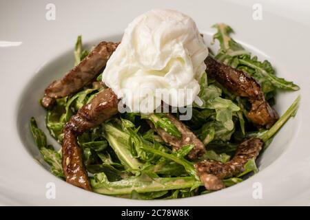 Salade de filet de veau et œuf poché. Salade chaude avec viande au restaurant Banque D'Images