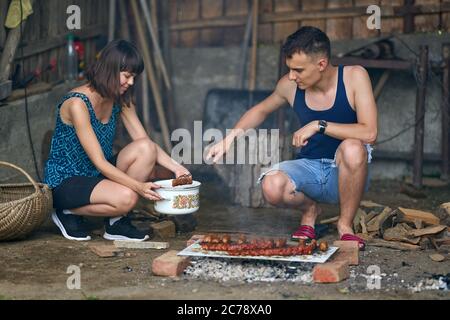 Un jeune couple heureux faisant un barbecue à la campagne Banque D'Images