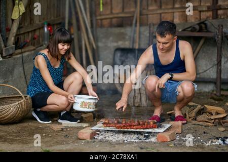 Un jeune couple heureux faisant un barbecue à la campagne Banque D'Images