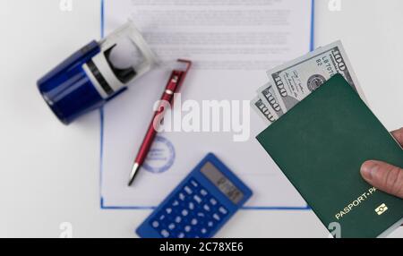 Main tient le passeport vert avec des dollars américains sur le fond des documents et le tampon en caoutchouc. Concept - corruption et briber Banque D'Images