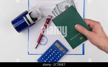 Main tient le passeport vert avec des dollars américains sur le fond des documents et le tampon en caoutchouc. Concept - corruption et briber Banque D'Images