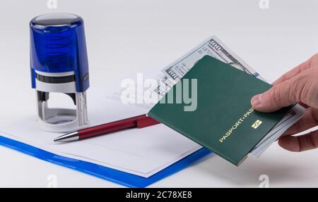 Main tient le passeport vert avec des dollars américains sur le fond des documents et le tampon en caoutchouc. Concept - corruption et briber Banque D'Images