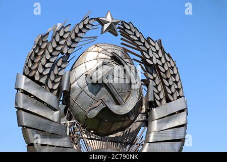 Armoiries de l'URSS, symbole communiste et socialiste. Emblème soviétique en métal sur fond bleu ciel Banque D'Images