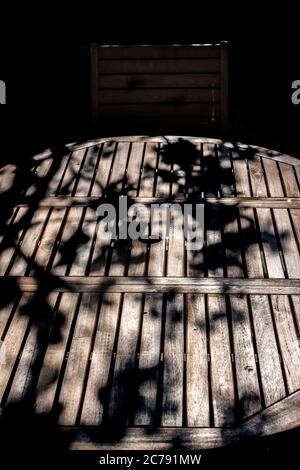 les branches créent des ombres sur une table de jardin en bois, Banque D'Images