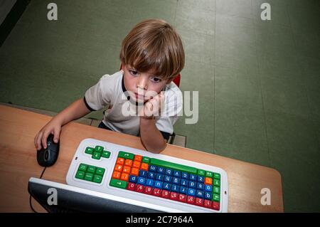 Petit garçon ordinateur Internet maternelle en ligne enfant 4-6 ans études pensives à l'école maternelle ordinateur avec souris dans la salle de classe de réception Banque D'Images