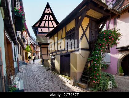 EGUISHEIM rue du Rempart Eguisheim village viticole médiéval avec couple touristique qui s'est promené dans la rue pavée historique Eguisheim Alsace France Banque D'Images