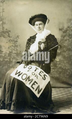 Suffragette assise, carte postale 1910 d'un militant pour les votes pour les femmes avec l'affiche drapée sur ses genoux Banque D'Images