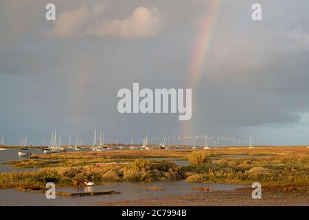 Début de soirée à Brancaster Staithes avec un double arc-en-ciel et des voiliers à l'ancre dans la lumière classique du soir Banque D'Images