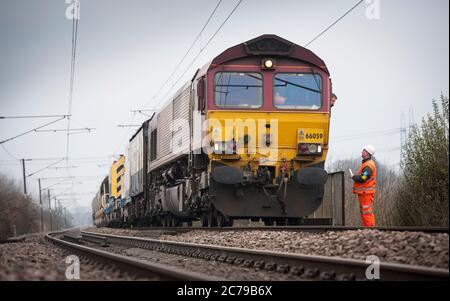 Locomotive diesel de classe 66 dans la livrée EWS transportant des wagons de ballast de réseau ferroviaire sur une partie de chemin de fer au Royaume-Uni. Banque D'Images