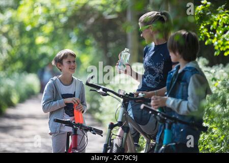 Mère et fils buvant de l'eau sur une promenade en vélo Banque D'Images