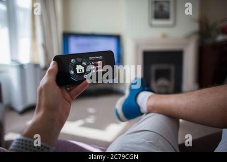 POV Homme vérifiant la sécurité à la maison sur le smartphone dans le salon Banque D'Images