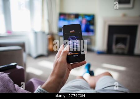 POV Homme vérifiant la télécommande de voiture sur le smartphone dans le salon Banque D'Images