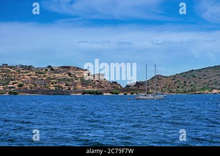 Vue sur l'île de Spinalonga et la forteresse vénitienne, la Crète, la Grèce et le yacht flottant par une journée d'été claire Banque D'Images