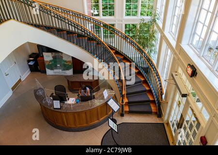 Washington, DC, Etats-Unis -- 14 juillet 2020. Une réceptionniste masquée est assise derrière des cloisons en verre au Hillwood Estate à Washington, DC. Banque D'Images